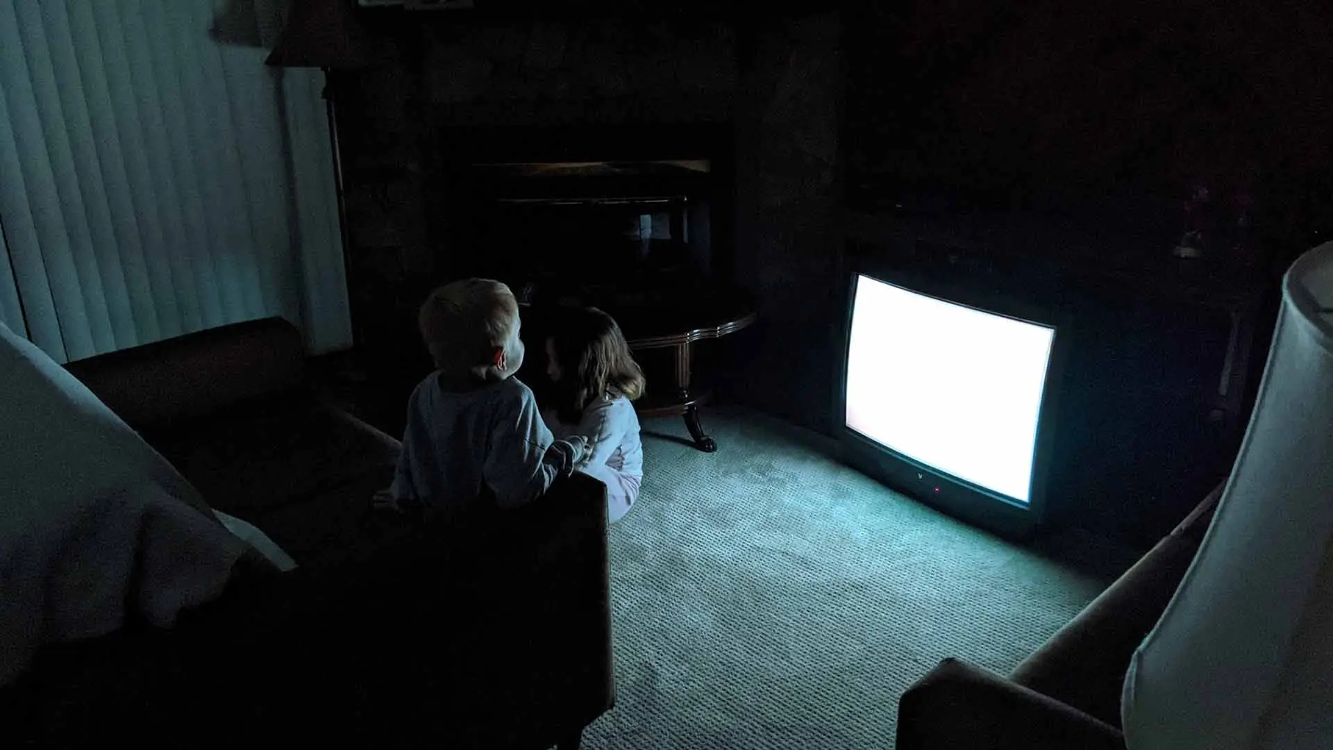 دو کودک در فیلم Skinamarink از شدت ترس در حال تماشا کردن برفک تلویزیون