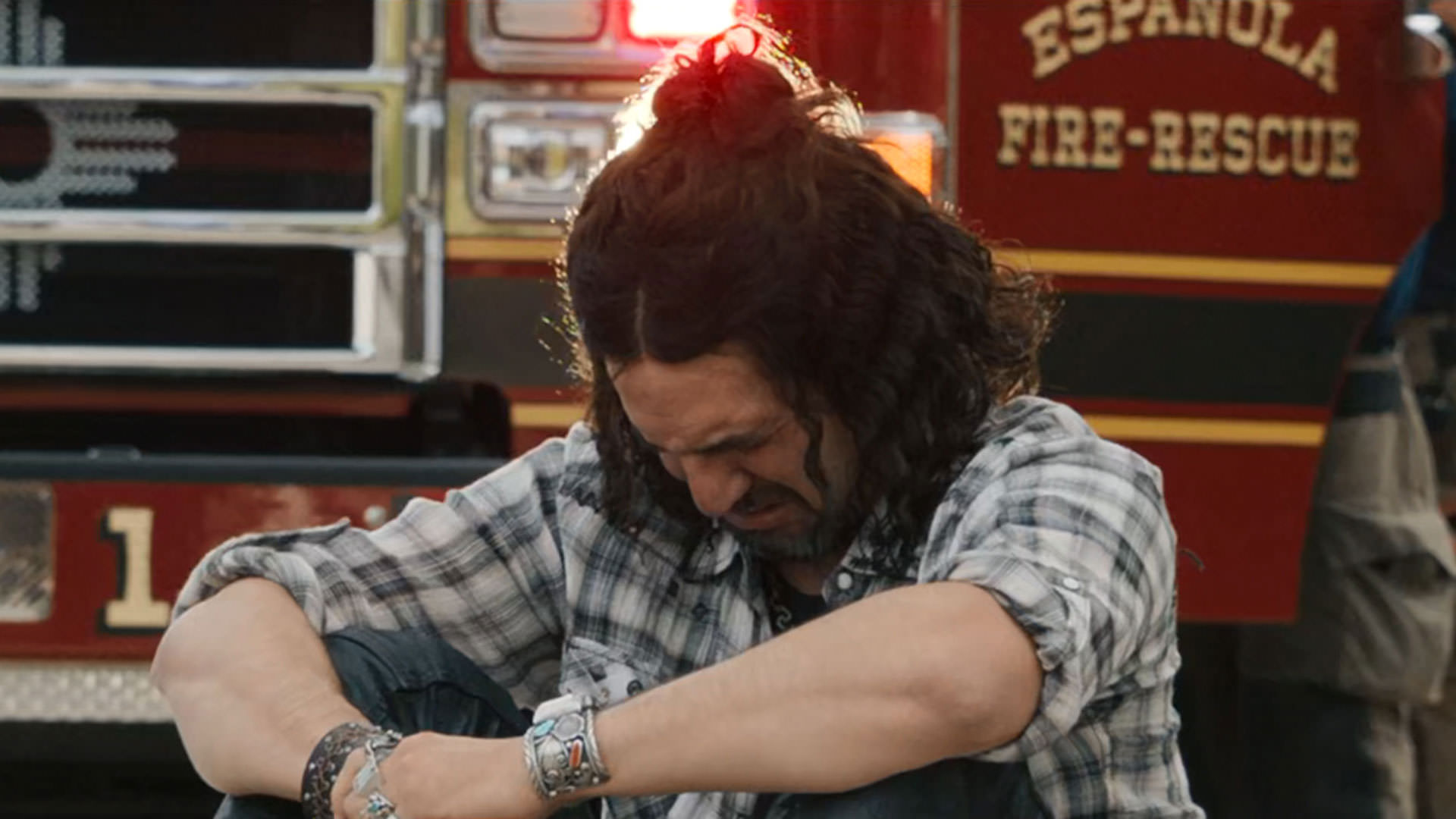 بنی سفدی نشسته روی زمین مقابل یک ماشین آتش‌نشانی گریه می‌کند در نمایی از سریال نفرین به کارگردانی بنی سفدی