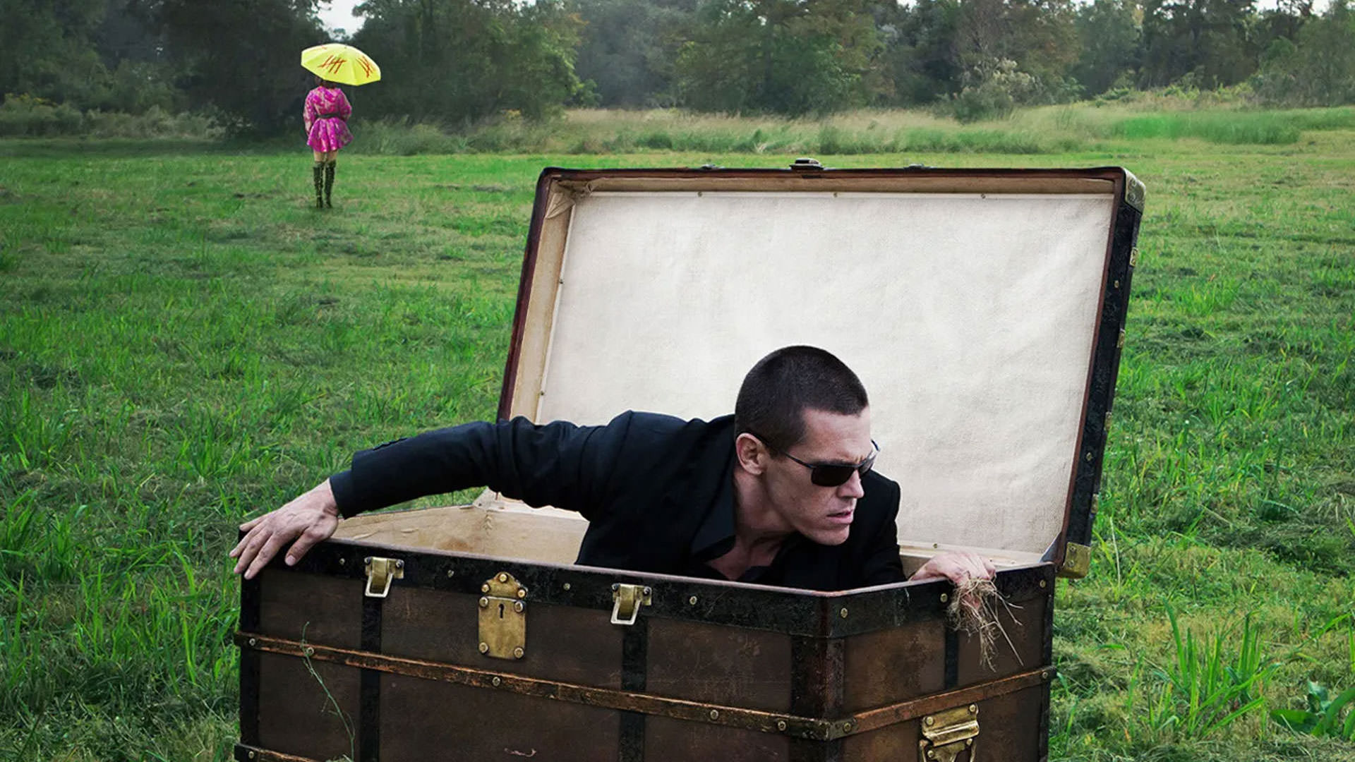 جاش برولین با لباس و عینک مشکی در حال بیرون آمادن از یک صندوق بزرگ در میان چمن‌ها در نمایی از فیلم اولدبوی به کارگردانی اسپایک لی