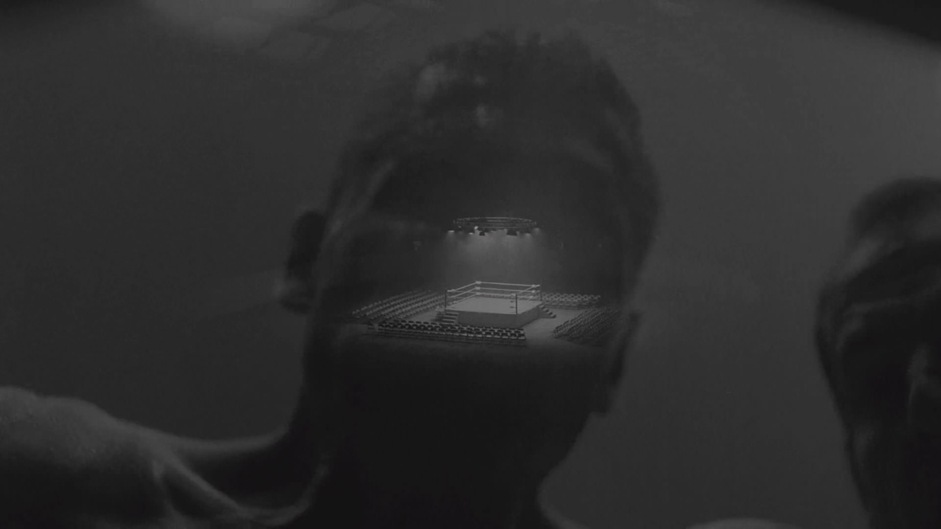 نمایی سیاه و سفید از یک رینگ خالی کشتی کج که با تصویری از یک مرد ادغام شده است در نمایی از فیلم پنجه آهنی به کارگردانی شان دورکین