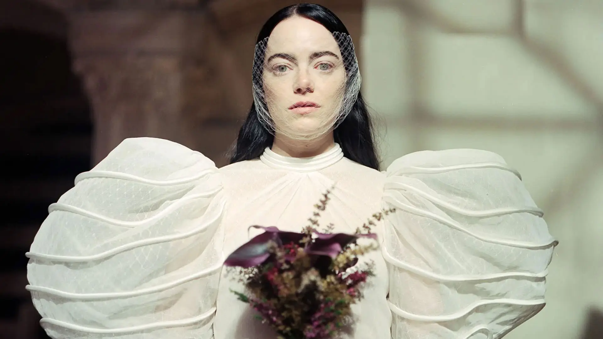 اما استون با یک لباس قدیمی عروس بر تن و دسته گلی در دست در نمایی از فیلم بیچارگان به کارگردانی یورگوس لانتیموس