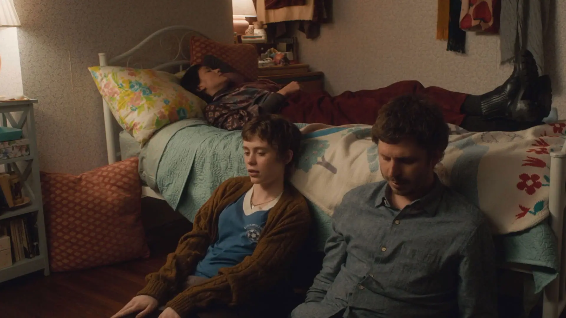 مایکل سرا نشسته کنار سوفیا لیلیس پایین تختی که هانا گروس روی آن خوابیده است در نمایی از فیلم بزرگ‌سالان به کارگردانی داستین گای دفا