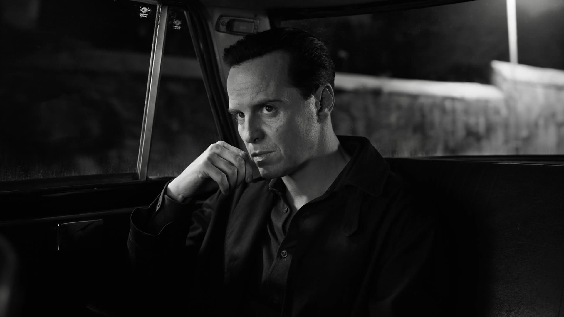 اندرو اسکات نشسته داخل یک ماشین در عکسی سیاه و سفید از سریال ریپلی به کارگردانی استیون زایلیان