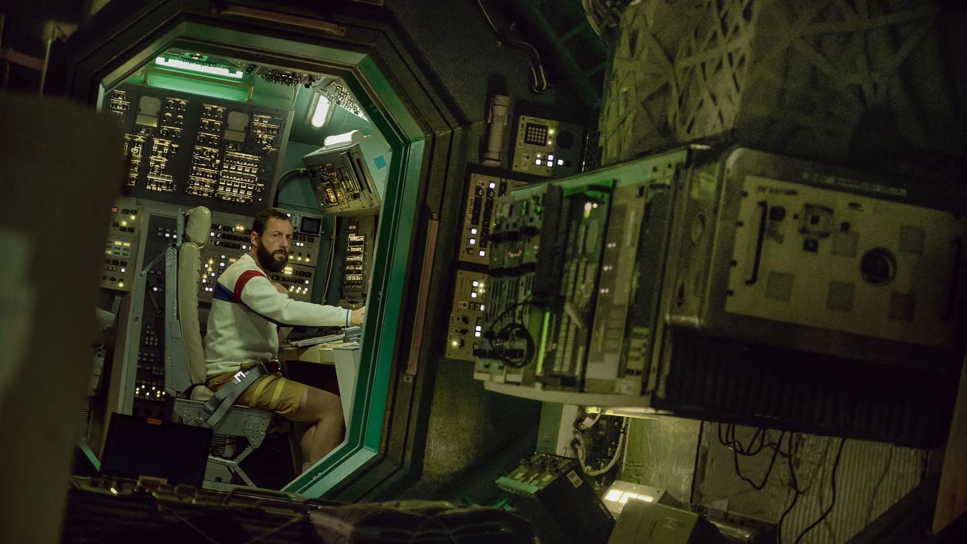 آدام سندلر در صحنه ای از فیلم فضانورد جان رنک در داخل یک سفینه فضایی نشسته است