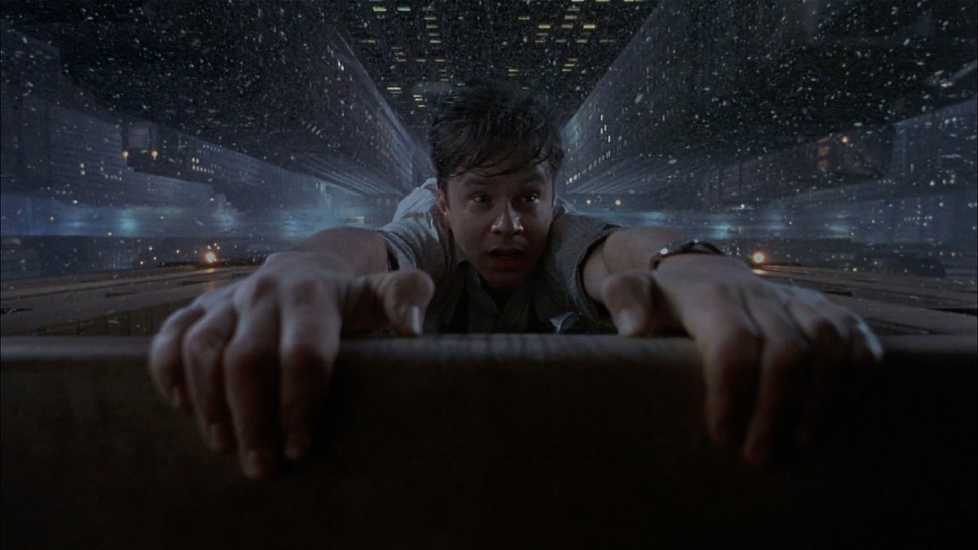 تیم رابینز در صحنه‌ای از فیلم برادران کوئن، The Hudsucker Substitute، شب‌ها از لبه یک آسمان‌خراش آویزان می‌شود.