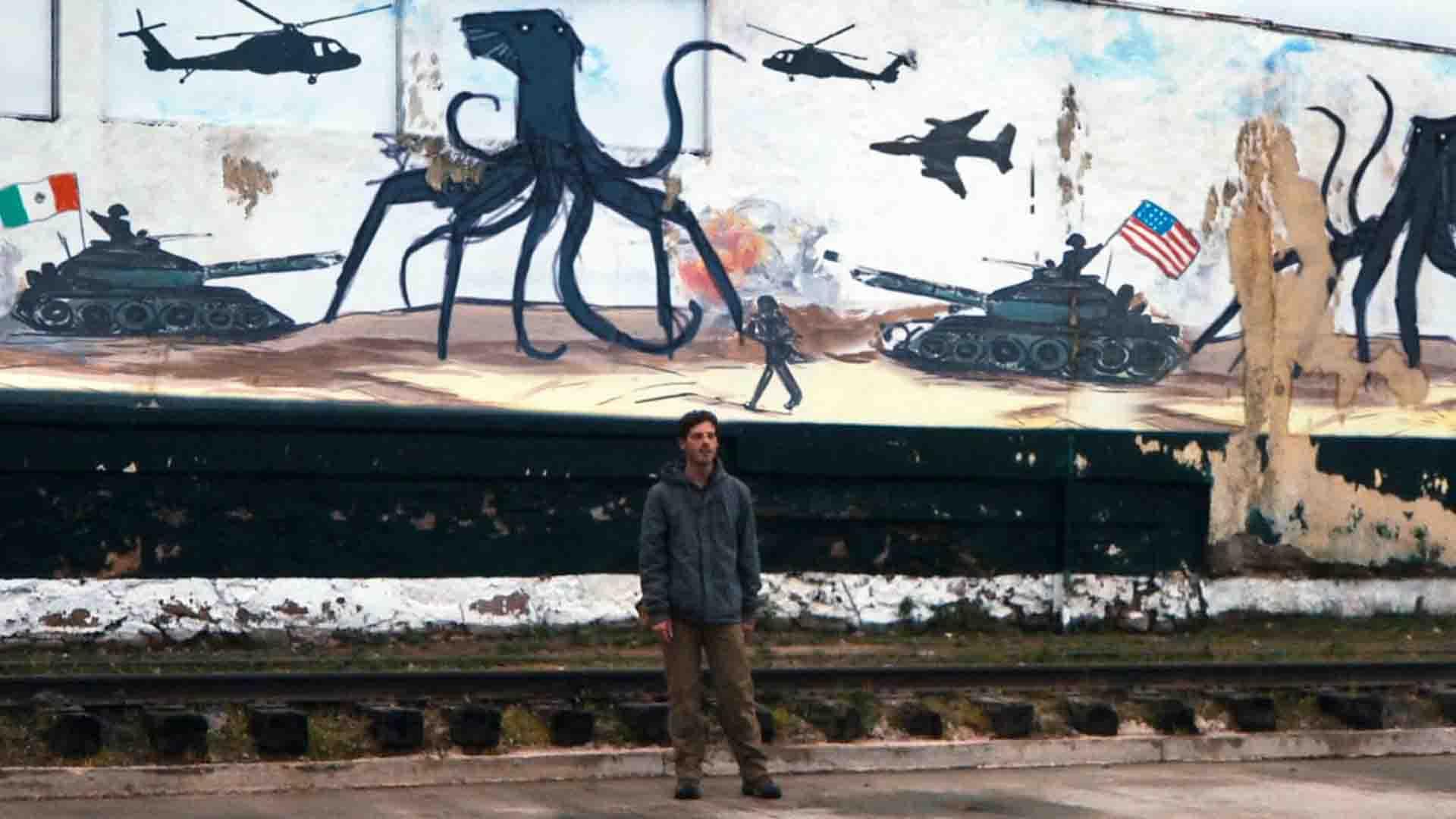 مردی مقابل دیواری پر از نقاشی در فیلم Monsters 