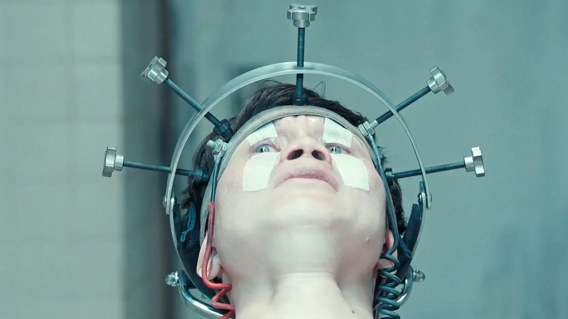 هوئا شوندی در حالی که سرش داخل دستگاهی فلزی ثابت نگه داشته‌ شده است با چهره‌ای نگران به شکنجه شدن واکنش نشان می‌دهد در نمایی از سریال هواخواه